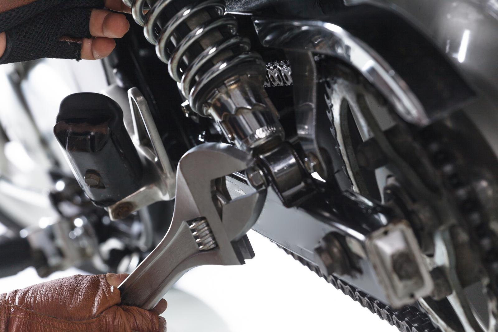 Adjusting motorcycle chain with a wrench